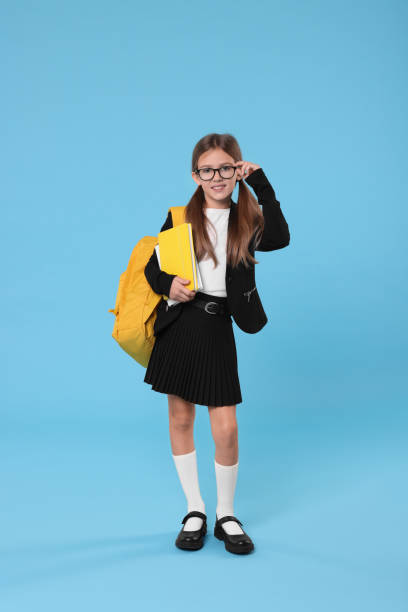 istock Happy schoolgirl with backpack and books on light blue background 1948271728
