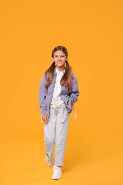 istock Happy schoolgirl with backpack on orange background 1948274849