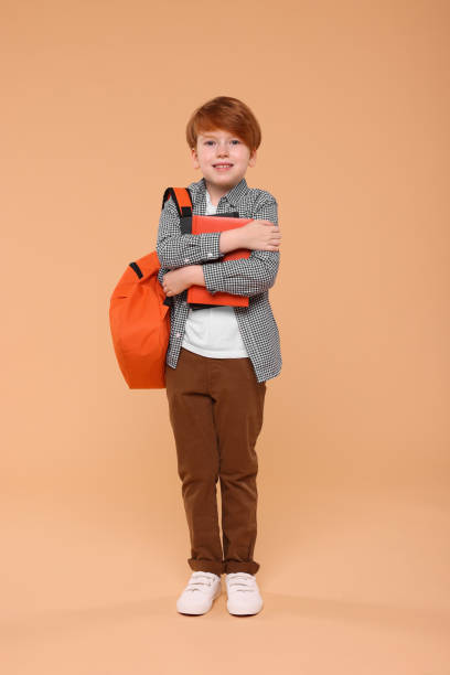 istock Smiling schoolboy with backpack and books on beige background 1948276387