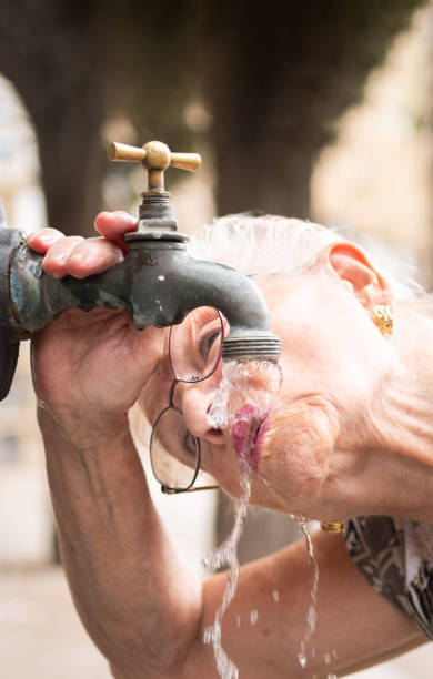 istock elderly woman drinking water from a public fountain 1948301037