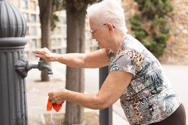 istock elderly woman using a public water fountain 1948301039