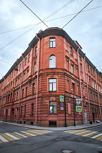 Unusual corner of red old residential building in the historical center of St. Petersburg, Russia. Cloudy evening sky