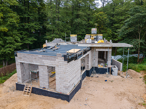 New residential house under construction with cinder blocks and building materials in a wooded area