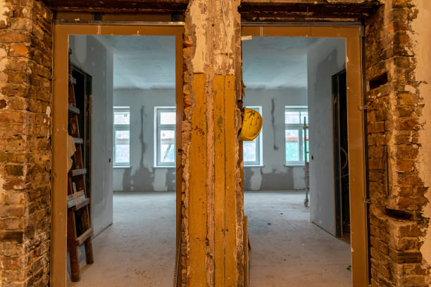 Abandoned building interior in disrepair with debris, exposed pipes, and missing doors awaiting renovation