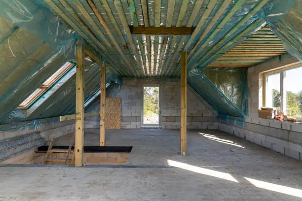 Spacious attic under construction with thermal insulation and skylights in a new home