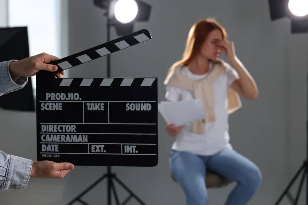 istock Casting call. Emotional woman performing while second assistance camera holding clapperboard against grey background in studio, selective focus 1948356214