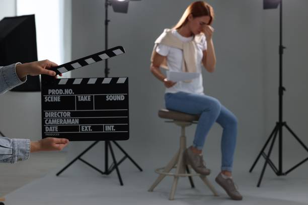 istock Casting call. Emotional woman performing while second assistance camera holding clapperboard against grey background in studio, selective focus 1948356633