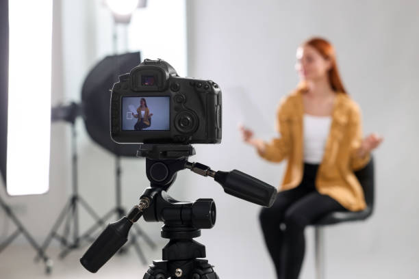 istock Casting call. Woman performing in front of camera against light grey background at studio, selective focus 1948358855