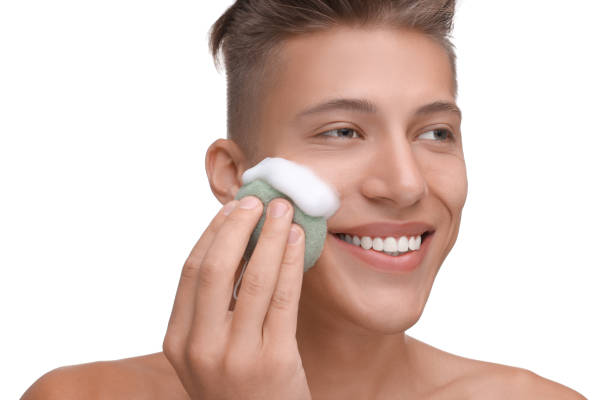 istock Happy young man washing his face with sponge on white background 1948414588
