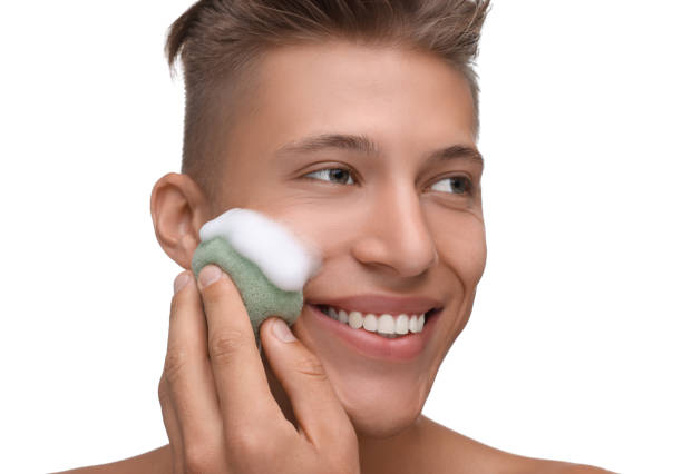 istock Happy young man washing his face with sponge on white background 1948414589