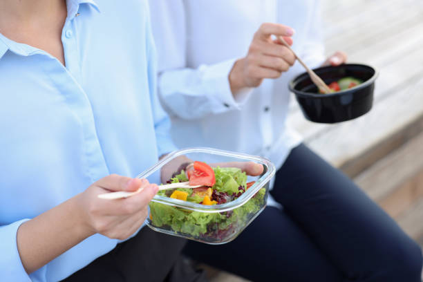 istock Business people eating from lunch boxes outdoors, closeup 1948439377