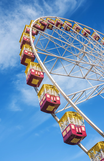 Cars of a Ferris wheel against a sunny blue sky