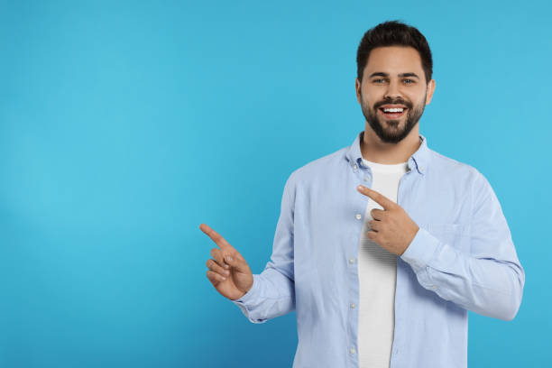 istock Special promotion. Smiling man pointing at something on light blue background. Space for text 1948443639
