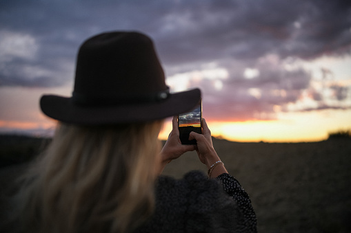 Young woman takes photo from vehicle at sunset