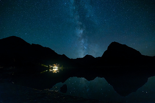 Milky Way and stars reflecting on the water of swift current lake, in Glacier National Park, Montana.