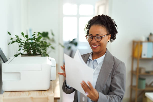 istock Young smiling businesswoman using printer at the office 1948600162