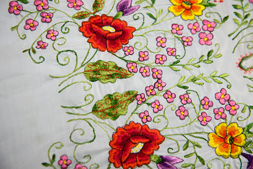 zoom view of a handmade multicolor Mexican embroidery on cotton fabric, flowers, birds and geometric figures typical of Mexican crafts and cultures