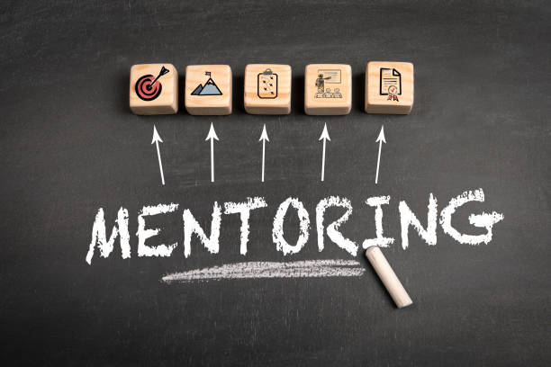 istock Mentoring. Wooden blocks on a dark chalkboard background 1948613296