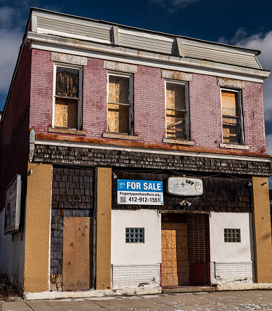 Pittsburgh, Pennsylvania, USA January 14, 2024 A former bar and apartment, now abandoned and boarded up on Hamilton Avenue in the Homewood neighborhood and for sale on a sunny winter day