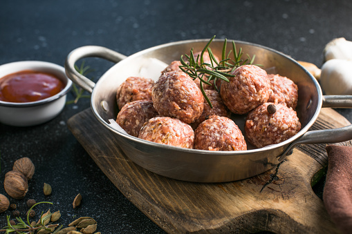 Raw meatballs in pan on the wooden cutting board