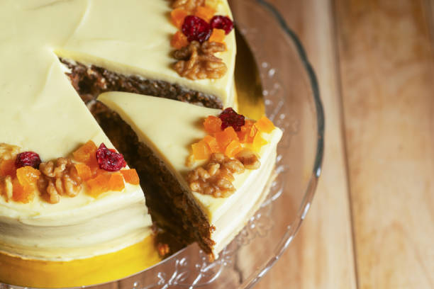 Sliced carrot cake with cream cheese frosting on a glass cake stand
