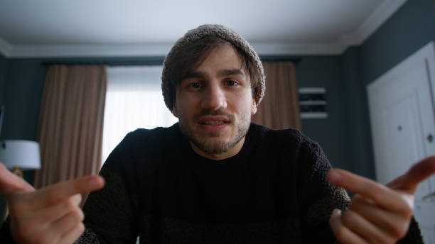 istock A man with beanie vlogger doing online video chat call, record vlog blog talking to camera looking at webcam at home. Videocall and social media vlogging concept 1948804033