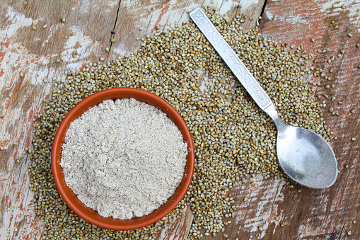 Pearl millet powder in a bowl on wooden background top view