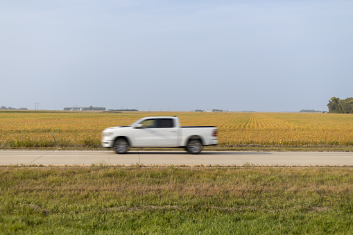 White Pickup Truck Speeding Along Rural Road by Golden Fields