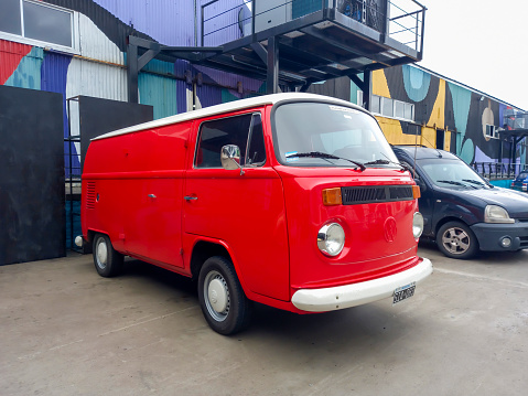 Avellaneda, Argentina - May 6, 2023: Old red 1970s Volkswagen Type 2 T2 Transporter panel delivery van at a classic car show. Industrial background