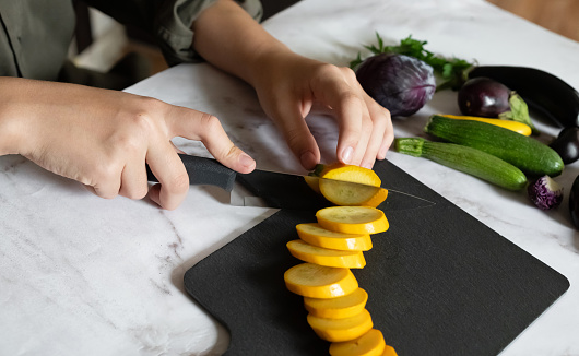 Slicing zucchini on a cutting board. Ripe zucchini on a gray background. Top view, horizontal.