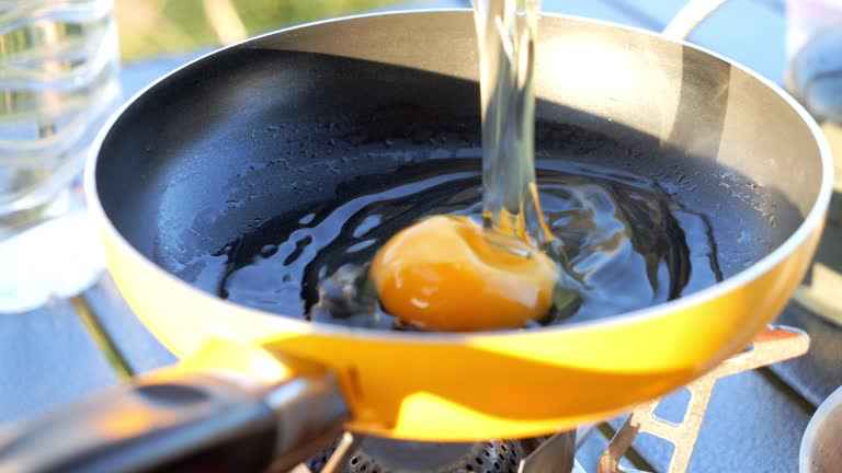 Cracking an egg into a frypan for making breakfast.