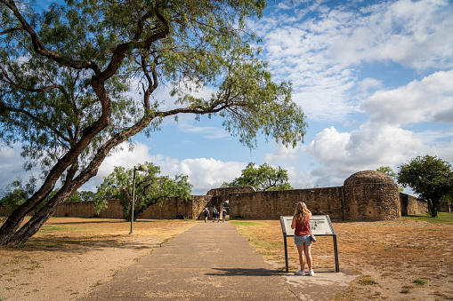 San Antonio, Texas, USA - July 5, 2023: Female tourist looks at the sign outside the Mission San JosÃ©, built in 1720, known as the Queen of the Missions. s, USA