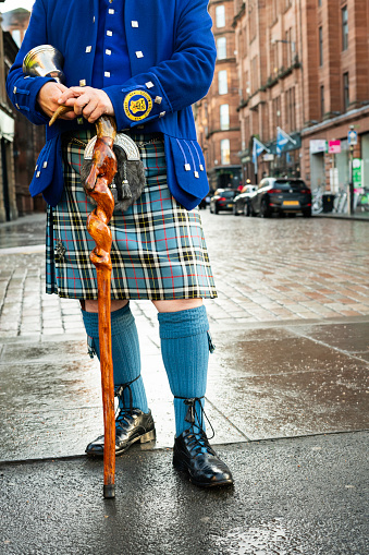 Piper playing the bagpipes in Scottish kilt against blue sky