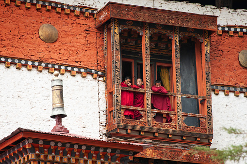 Thimpu, Bhutan - April 24, 2008: Three male monk students look out the balcony at at Tango Goemba Monastery; the residence of reincarnated Gyalse Tenzin Rabgye; Buddist college