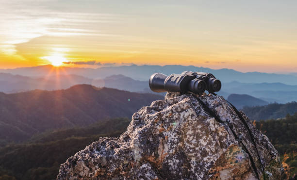 istock binoculars on top of rock mountain at beautiful sunset background. 1949051383