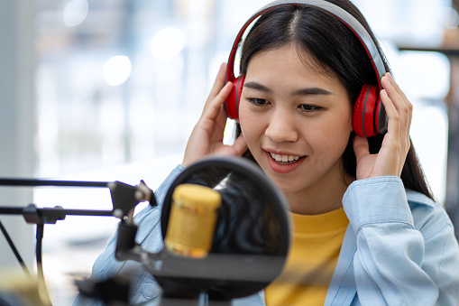 Close-up of a young woman wearing headphones recording a podcast in a studio