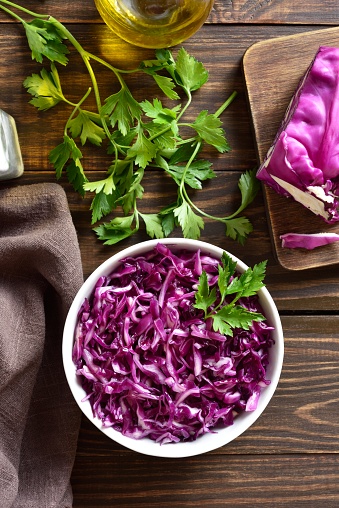 Red cabbage in bowl over wooden background. Top view, flat lay