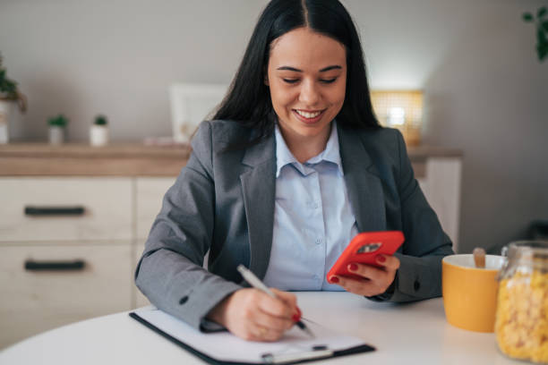 istock Businesswoman in a modern home office making notes on a clipboard 1949131070