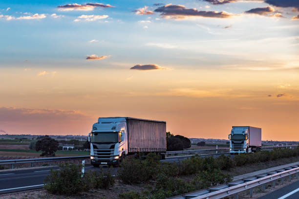 istock Two trucks driving on the highway under a dramatic sunset sky. 1949173237