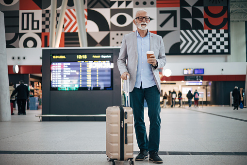 Senior man talking on smart phone while standing at train station