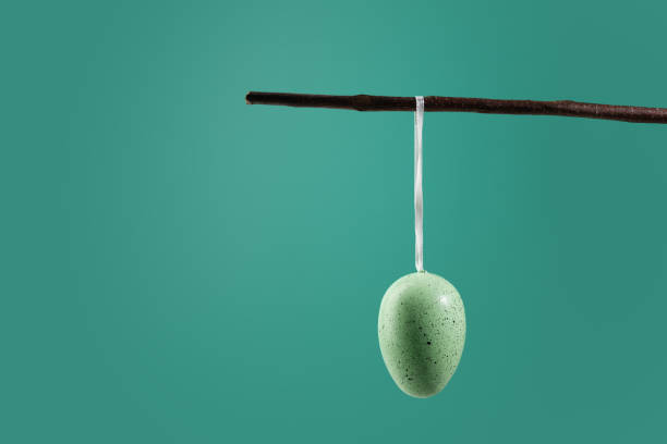 istock DIY Easter decoration, egg suspended from a branch, green background, festive card 1949175344