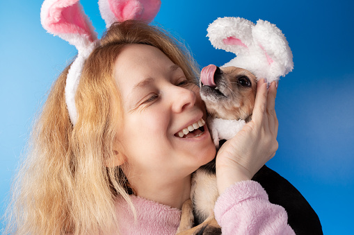 Woman and dog in bunny ears, Easter background, festive pet and owner