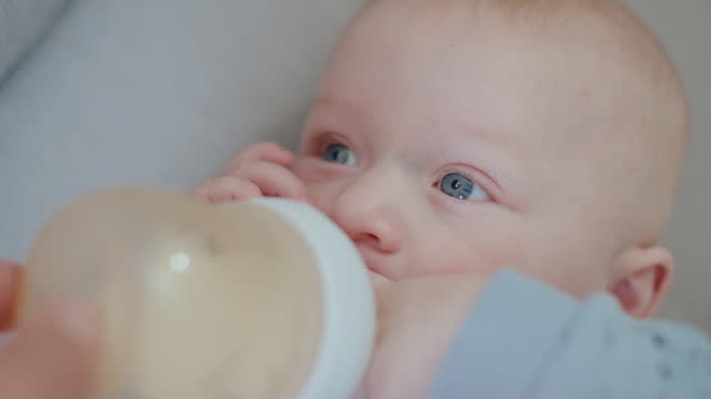 SLO MO Directly Above Handheld Shot of Baby Boy Drinking Milk from Bottle while Lying on Sofa at Home