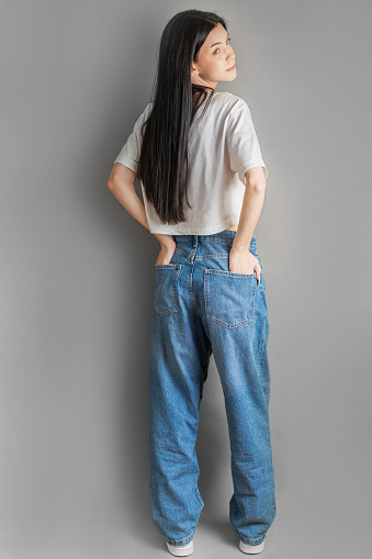 Full length portrait of a young teenager girl in a white T-shirt and jeans.
