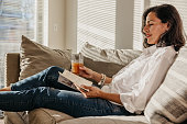 Woman enjoying a day off and reading a book on the couch