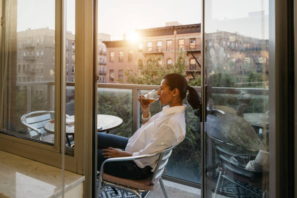 istock Woman relaxing with a drink sitting on the balcony 1949223912