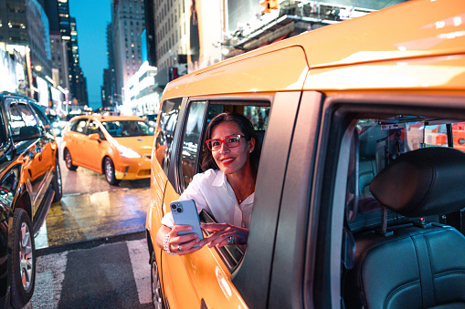Hispanic adult woman riding a taxi in Manhattan looking out of the car window.