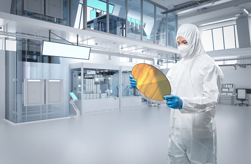 Worker or engineer wears protective or coverall suit with silicon wafer for semiconductor manufacturing