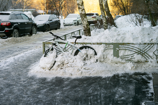 a bicycle tethered to the fence and covered with snow, city scene