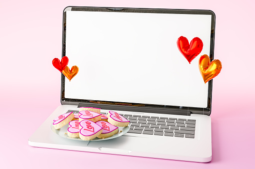 3d rendering of heart shaped cookie placed on laptop against light pink surface in modern studio